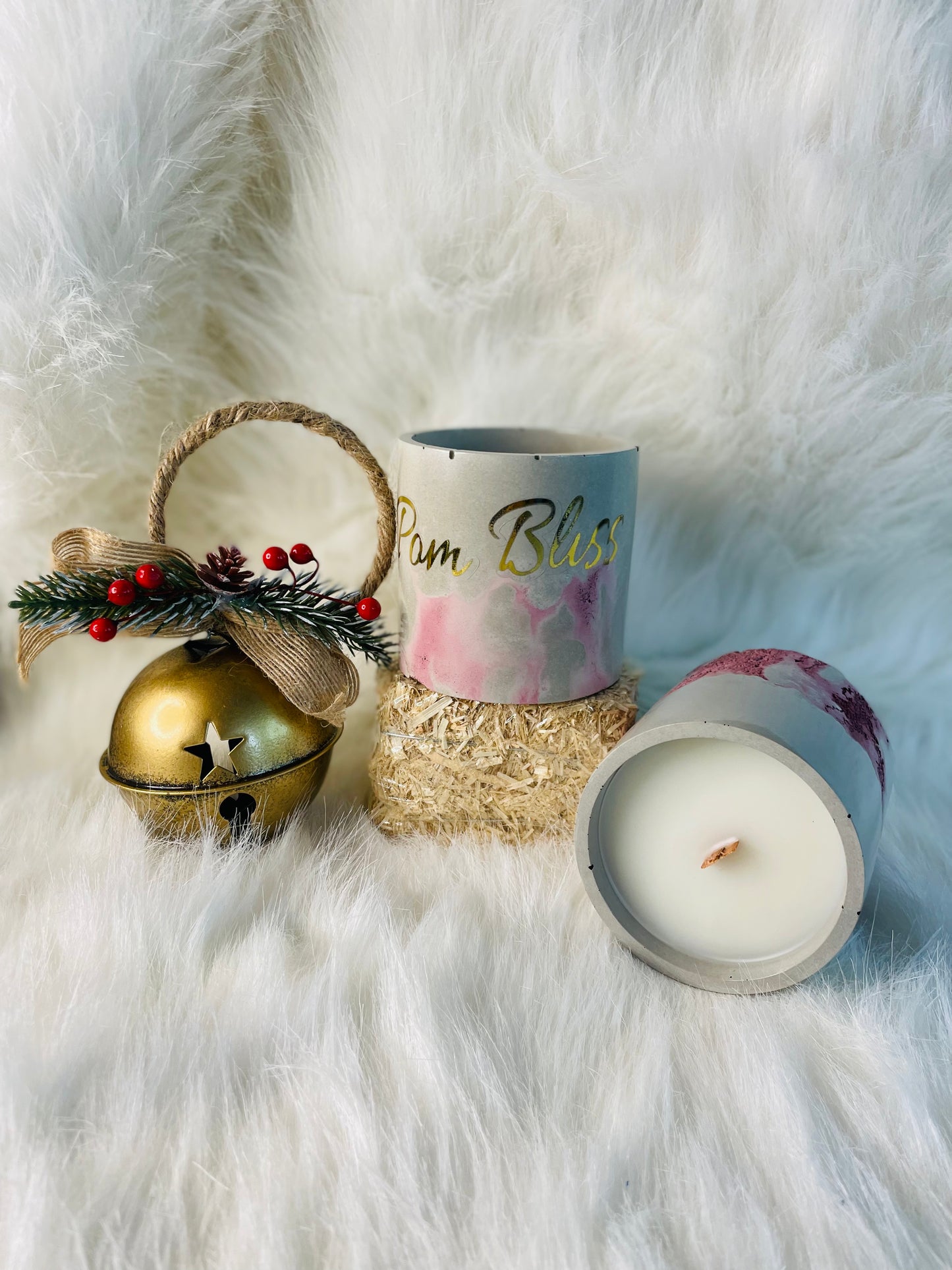 Pom Bliss candle in a cement vessel along side a bell with berries on it 