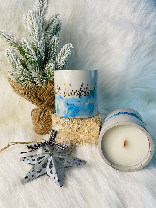 Winter Wonderland candle in a cement vessel on a hay bin surrounded by a tree with snow and a star 